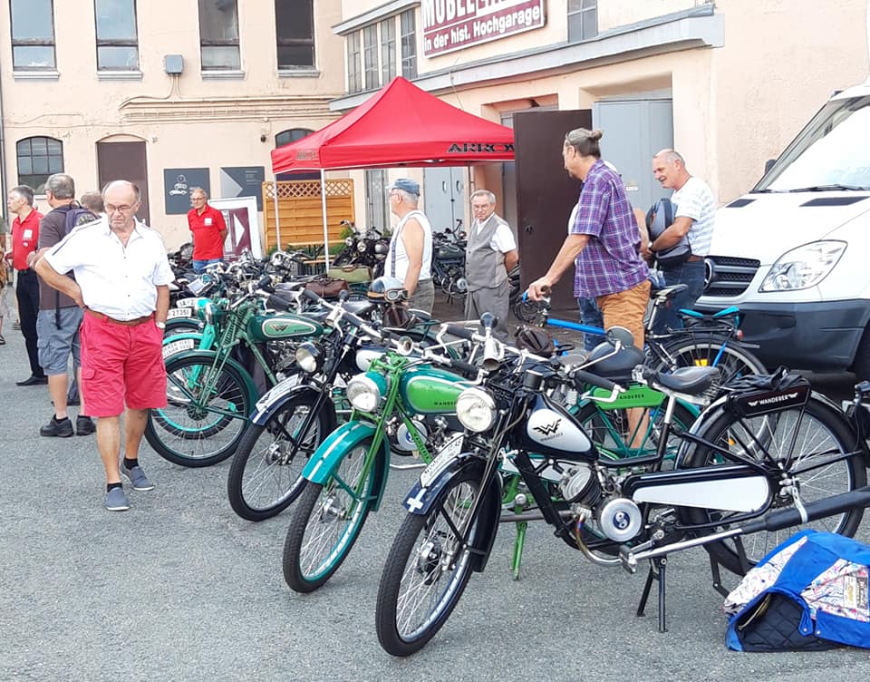 Kleinmotorräder und Besucher vor dem Museum