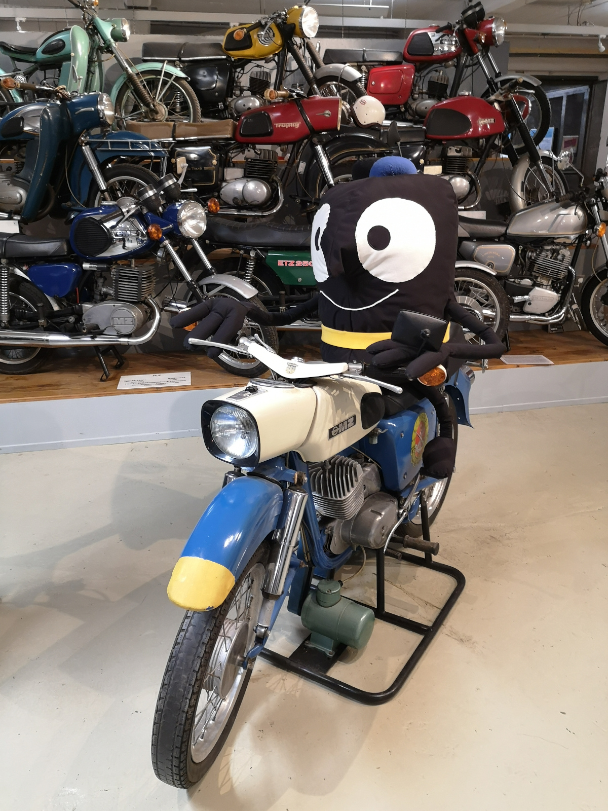 Edda, das Maskottchen der Europäischen Woche der Mobilität, auf einem historischen Motorrad