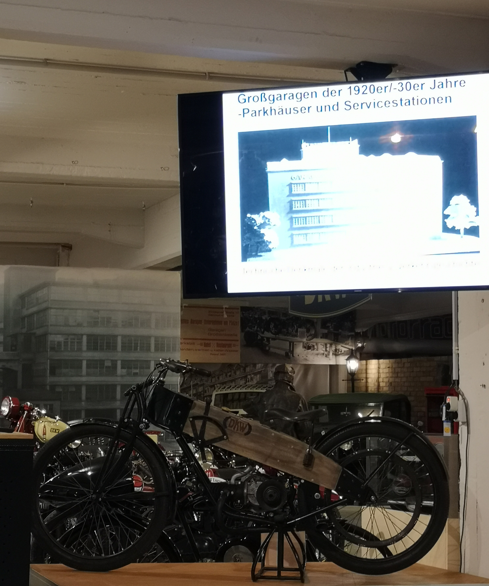 DKW-Motorrad unter dem Bildschirm mit einer Folie aus dem Vortrag von Thomas Morgenstern