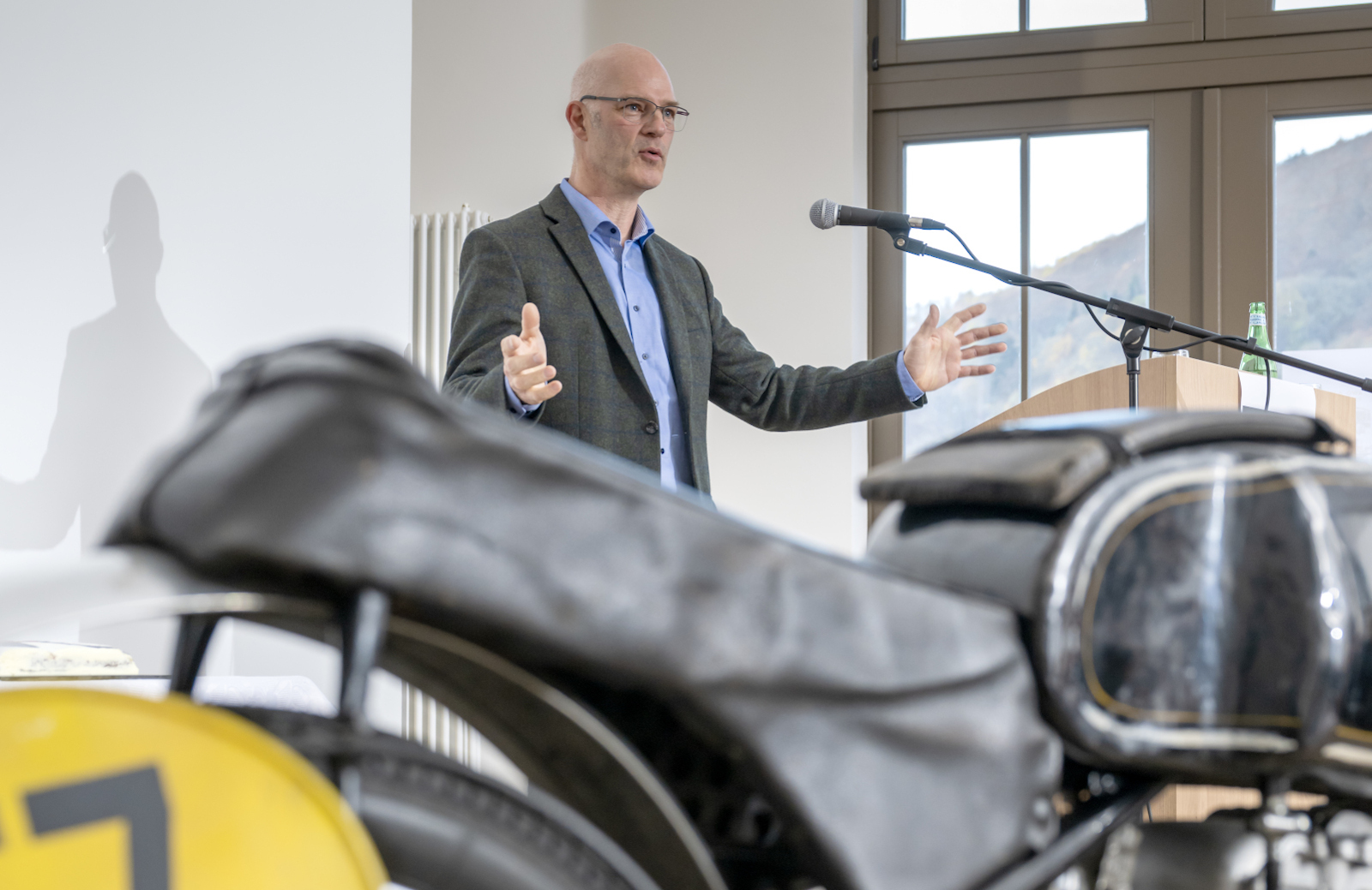 Der Autor Henrik Fanger beim Vortrag mit Motorrad im Vordergrund, Foto: Detlev Müller